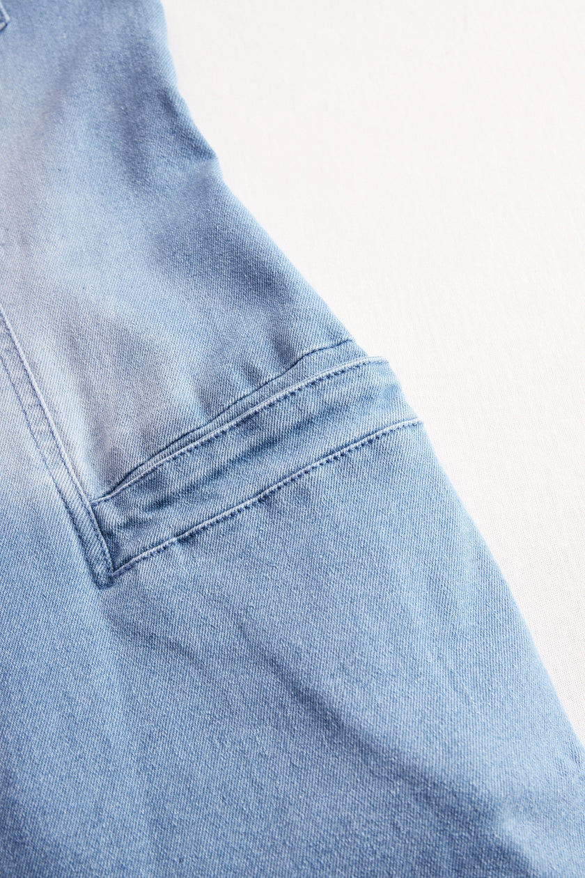 Light blue denim flared long sleeve jumpsuit for women by FJØRNA, featuring wide-leg pants and a stylish, casual fit.