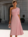 FJØRNA blush pink one-shoulder pleated midi dress displayed on a hanger, showcasing its elegant design and flowy fabric.