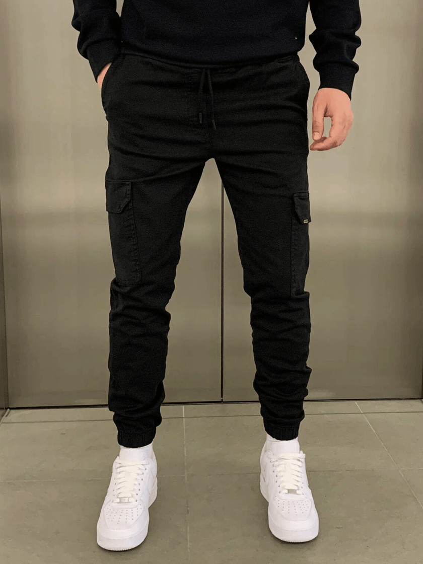 Men's black cargo jogger trousers by FJØRNA featuring a relaxed fit, multiple pockets, and tapered ankle design.