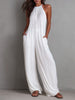 White pleated halter neck wide-leg resort jumpsuit for women by FJØRNA, shown with flowing fabric and stylish design.