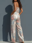 White floral satin halter neck wrap-front wide-leg jumpsuit for women by FJØRNA, featuring a stylish halter design and flowy wide-leg pants.