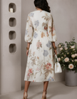 Ivory chiffon midi dress for women by FJØRNA featuring a V-neck and printed design, shown hanging on a white background.