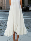 FJØRNA pleated halter neck flowing asymmetric midi dress with pleats and elegant silhouette, displayed on a model.