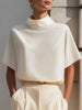 White high-neck minimalist blouse by FJØRNA, featuring draped design and long sleeves, suitable for stylish women's tops.