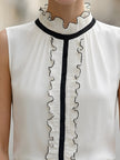Ivory sleeveless ruffle high-neck blouse for women by FJØRNA, showcasing elegant ruffle details and a high neckline.