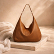 Large leather hobo bag for women by FJØRNA, showing a spacious brown leather bag with rounded shape and shoulder strap.