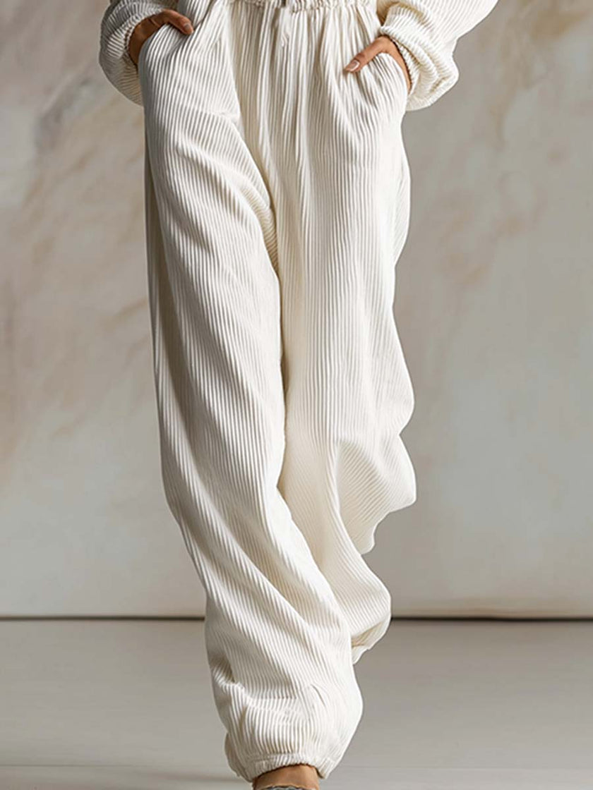 White corduroy hooded jumpsuit with zip front and long sleeves, women's pants by FJØRNA, shown on a model.