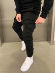 Men's black cargo jogger trousers by FJØRNA featuring relaxed fit, elastic waistband, and multiple utility pockets.