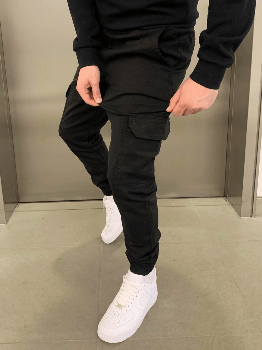 Men's black cargo jogger trousers by FJØRNA featuring relaxed fit, elastic waistband, and multiple utility pockets.