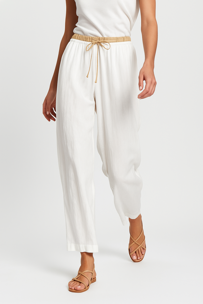 FJØRNA women's linen tapered trousers, lightweight pants with relaxed fit, shown in motion on a model.