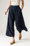 FJØRNA women's tapered linen trousers displayed on a model, featuring a relaxed fit and natural fabric texture.