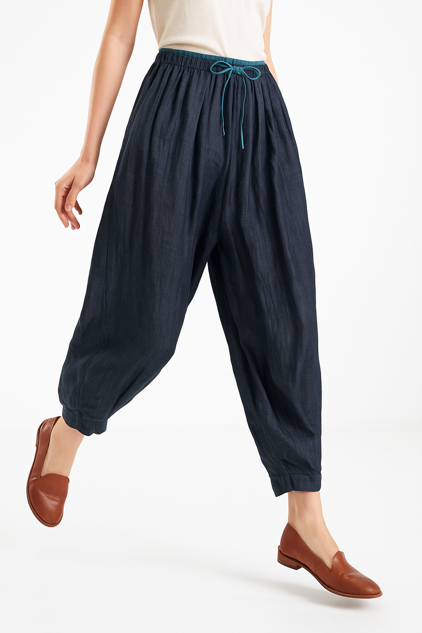 FJØRNA women's tapered linen trousers displayed flat, showcasing lightweight, breathable fabric and modern relaxed fit.