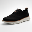 Men's breathable knit mesh trainers by FJØRNA with cushioned waffle-pod sole, displayed on a sleek shoe stand.