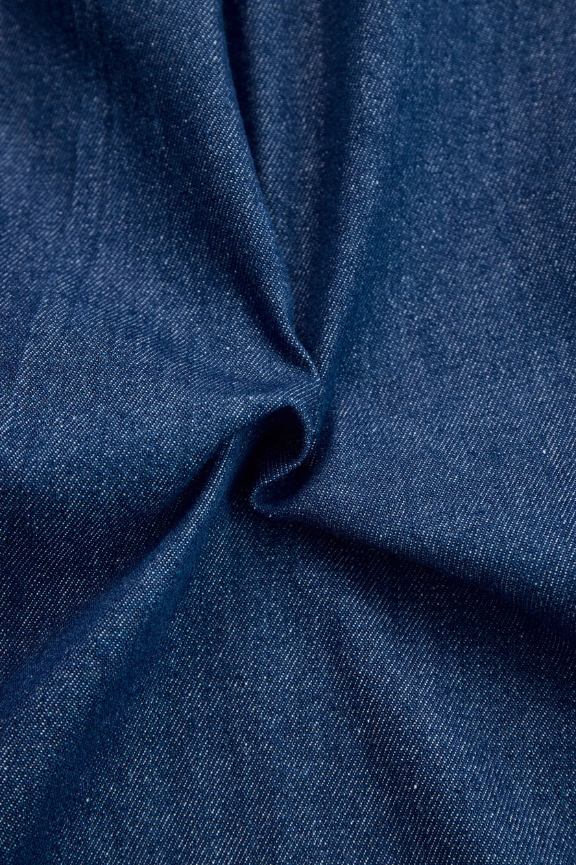 Dark blue FJØRNA denim jumpsuit with wide-leg pants and long sleeves, featuring topstitch detailing.