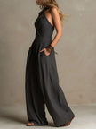FJØRNA charcoal pinstripe women’s halter neck wide-leg jumpsuit, front view showing fitted waist and flowing wide-leg pants.