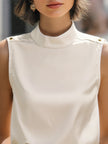 Ivory high-neck sleeveless satin blouse for women by FJØRNA, featuring a stylish white top with a fitted high neckline.