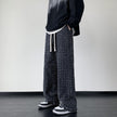 Men's black distressed trousers by FJØRNA, casual pants with ripped detailing and a relaxed fit, shown on a model.