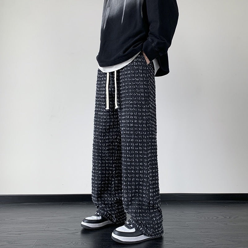 Men's black distressed trousers by FJØRNA, casual pants with ripped detailing and a relaxed fit, shown on a model.