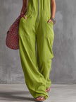 Bright green FJØRNA cotton linen zip-front women's jumpsuit styled as pants, with a relaxed fit and front zipper detail.
