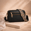 Black FJØRNA refined leather shoulder bag for women, featuring a sleek design and adjustable strap, on a neutral background.