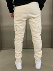 Cream cargo jogger trousers for men by FJØRNA, showing relaxed fit with multiple pockets and casual style.