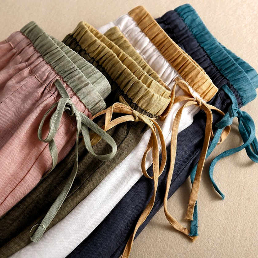 FJØRNA women's linen tapered trousers, lightweight pants with a relaxed fit, shown in a neutral color on a model.