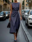 FJØRNA women's midi dress with round neck, sleeveless design and pleated details, perfect for elegant daytime wear.