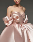 Light pink satin cocktail dress for women with sweetheart neckline, corset bodice, and bow detail by FJØRNA.