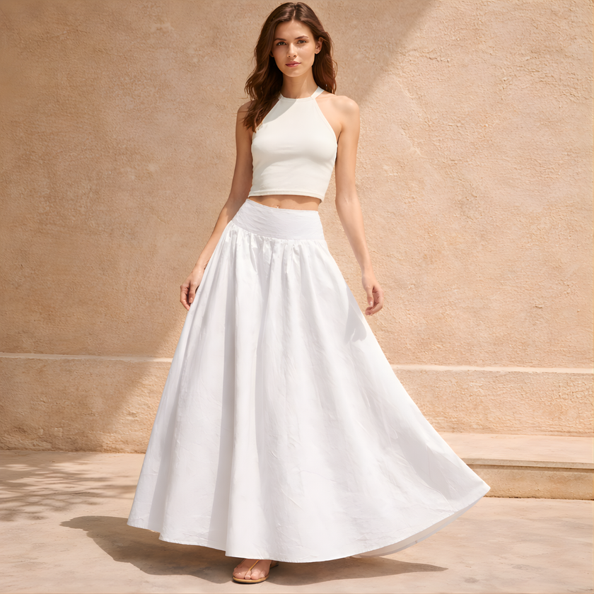 White cotton high-waist maxi skirt from FJØRNA, flowing and elegant, shown on a model with a relaxed fit and smooth fabric.