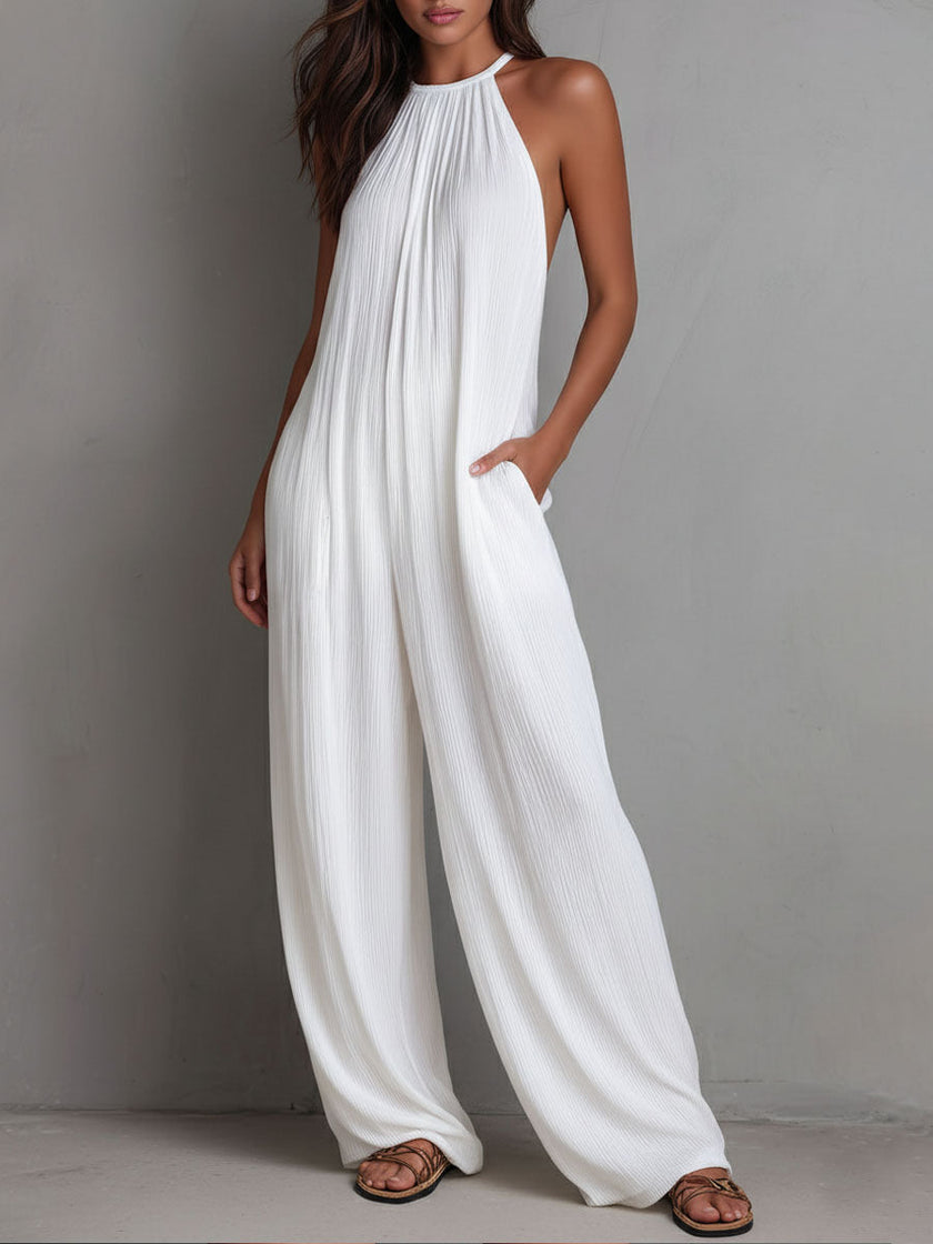 White pleated halter neck wide-leg resort jumpsuit for women by FJØRNA, featuring a stylish halter top and flowing wide-leg pants.