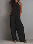 White pleated halter neck wide-leg resort jumpsuit for women by FJØRNA, featuring stylish pleats and flowing wide-leg pants.