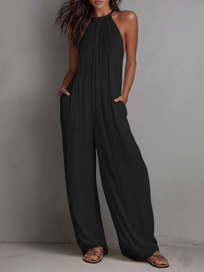 White pleated halter neck wide-leg resort jumpsuit for women by FJØRNA, featuring stylish pleats and flowing wide-leg pants.