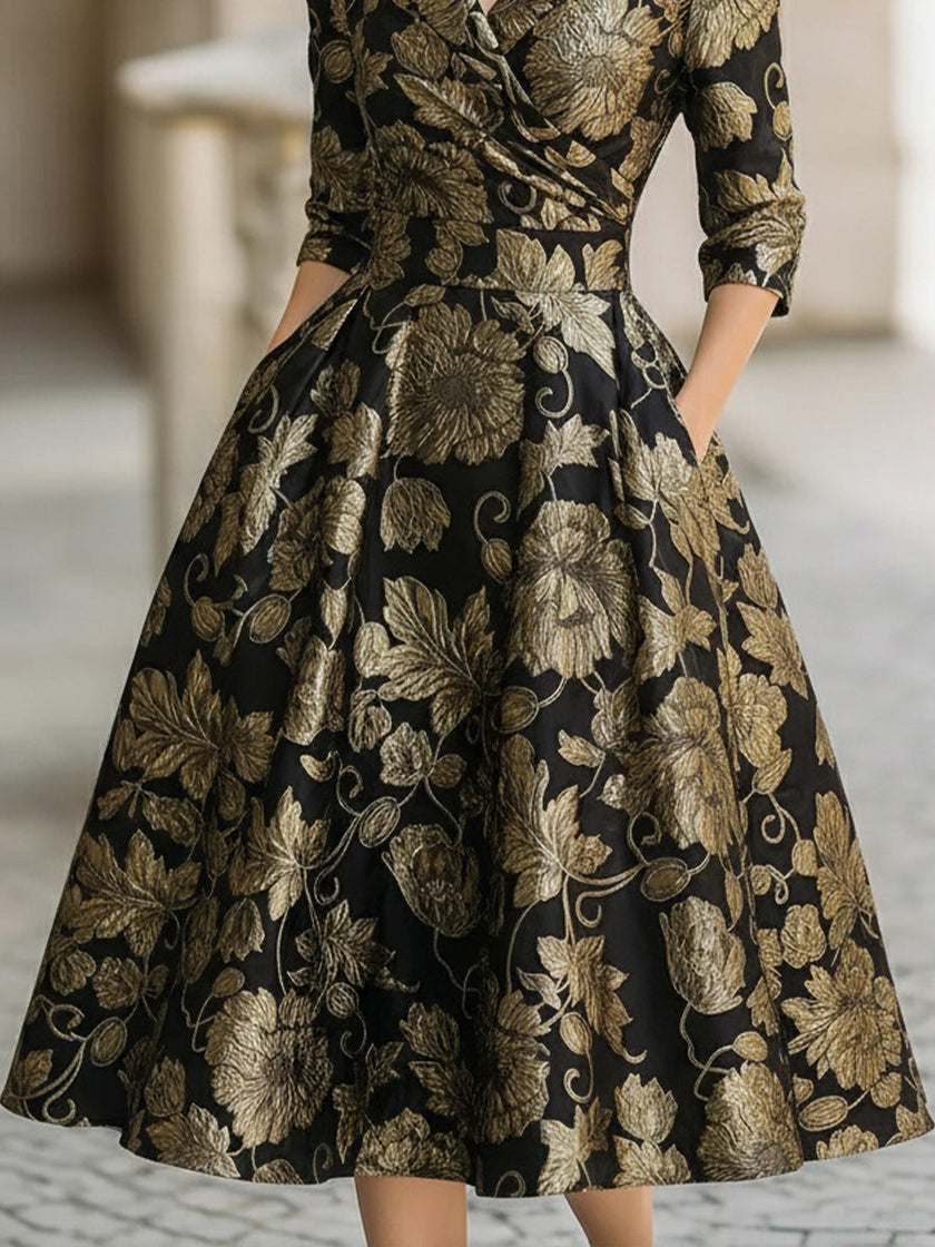 FJØRNA black and gold floral jacquard midi dress with a fitted silhouette and feminine tie detail at the waist.