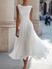 FJØRNA sleeveless pleated midi dress with draped neckline, perfect for wedding guests, shown in a light fabric on a model.