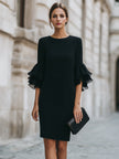 FJØRNA black ruffled sheer sleeve midi cocktail dress displayed on model with elegant design and flowing silhouette.