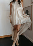 FJØRNA halter neckline sleeveless asymmetric women's maxi dress displayed on a model, featuring flowing fabric and elegant design.