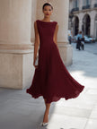 FJØRNA draped neck sleeveless pleated midi dress for wedding guests, featuring elegant flowy fabric and sophisticated style.