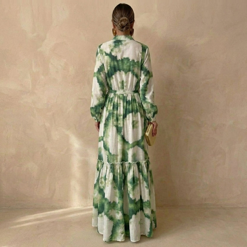 Back view of FJØRNA elegant women's maxi dress with V-neck and long sleeves, flowing fabric and fitted waist.
