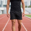 Men's black athletic shorts by FJØRNA with elastic waist and side slits, designed for comfortable active wear.