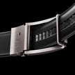Black vegan leather ratchet belt from FJØRNA, adjustable unisex belt with a sleek design and metal buckle on a black background.