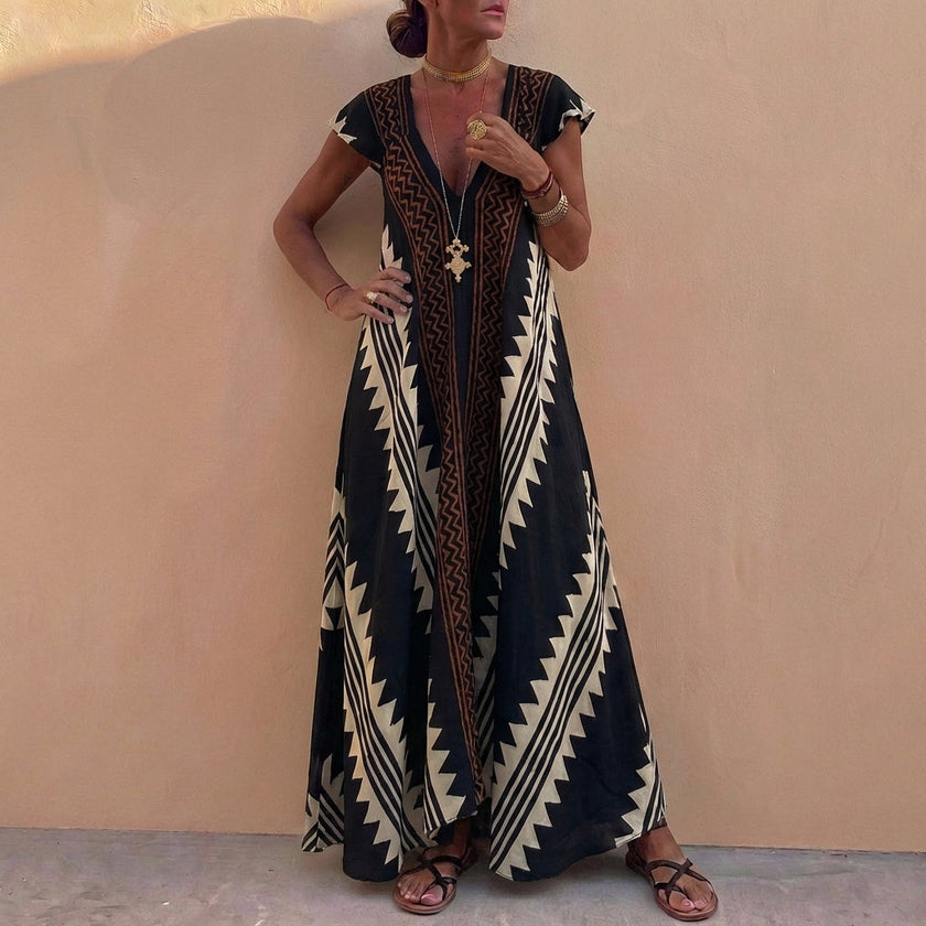 Black FJØRNA elegant maxi dress for women with geometric V-neck design and flowing silhouette.