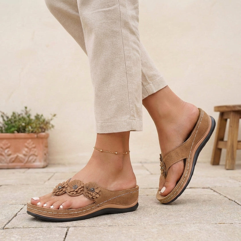 FJØRNA orthopedic open toe wedge flip-flops with floral embellishments, brown sandals with supportive design and decorative flower accents.