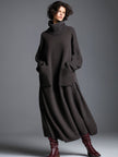 Brown knit maxi dress for women by FJØRNA, featuring a flowing silhouette and long sleeves, worn by a model in a casual setting.