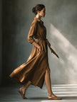 Brown FJØRNA maxi dress for women featuring a flowing silhouette and elegant design, displayed on a hanger.