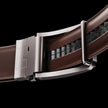 FJØRNA vegan leather ratchet belt in brown, adjustable unisex belt with sleek design on black background.