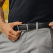 Close-up of FJØRNA black vegan leather ratchet unisex belt showing adjustable buckle and smooth leather surface.