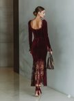 FJØRNA Burgundy velvet maxi dress with long sleeves and elegant flowing silhouette, perfect for evening occasions.