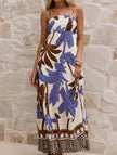 White tropical print cami maxi dress by FJØRNA with colorful floral patterns, flowing fabric, and adjustable straps.