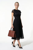 Elegant black floral lace pleated A-line maxi dress by FJØRNA, perfect for wedding guests, shown full-length.