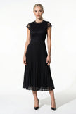 Black floral lace pleated maxi dress by FJØRNA, elegant A-line wedding guest dress with intricate lace details and flowing fabric.